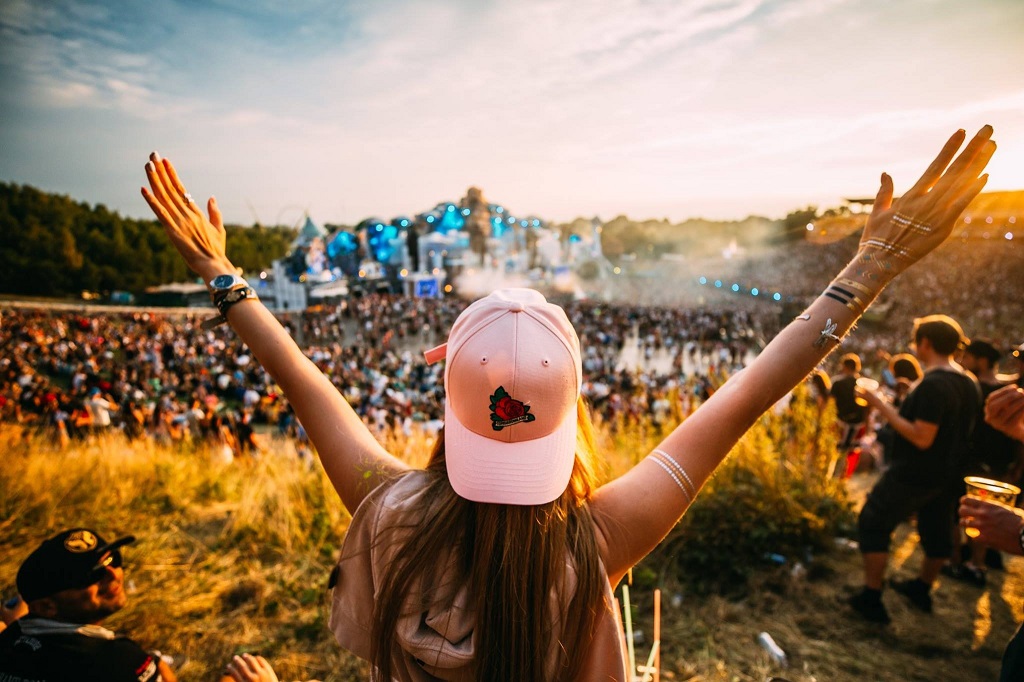Vibrant crowd dancing at Tomorrowland festival under colorful stage lights in Belgium, capturing the energy of budget EDM travel.